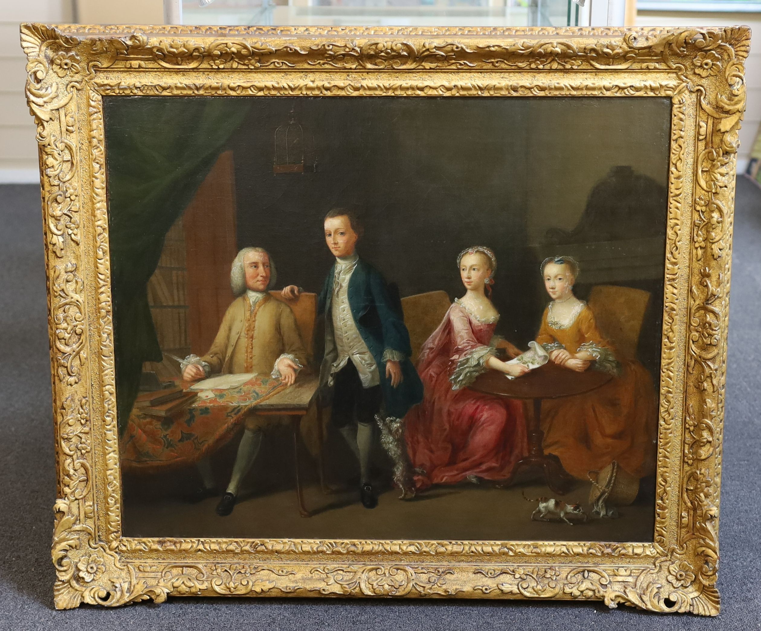 Manner of Arthur Devis (1712-1787), Family portrait, interior with a gentleman seated at a writing table, his son to one side and his wife and daughter holding needlework at a table, a cat at their feet, oil on canvas, 6